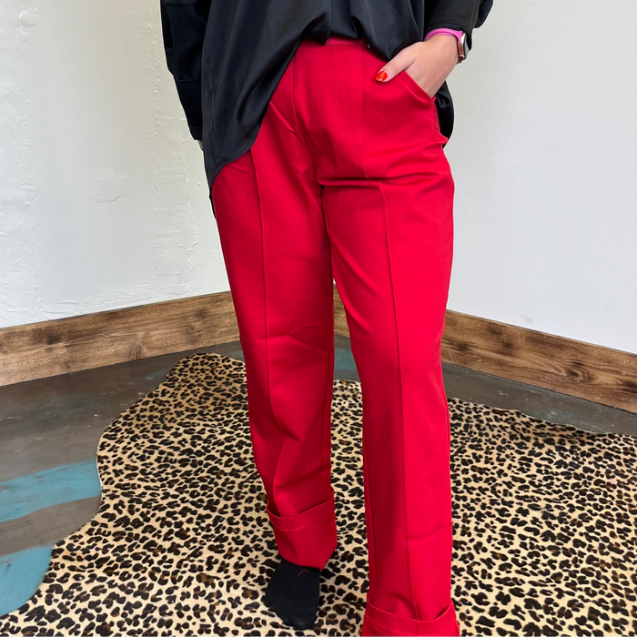 red pants standing in front of a mirror on a leopard print rug.