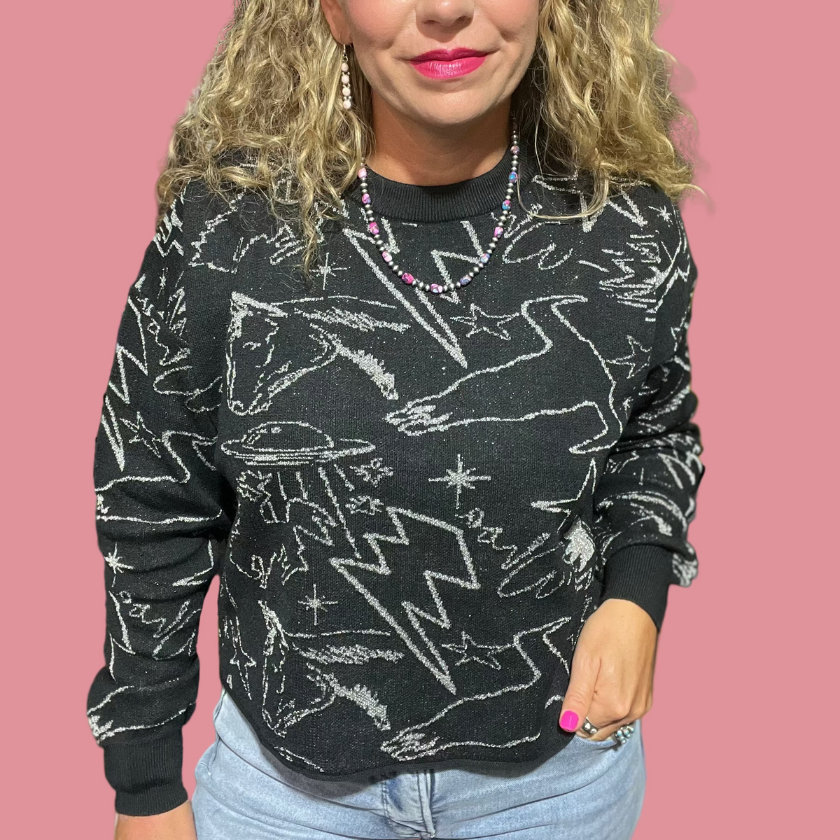 Woman wearing a black sweater with white patterns in an indoor setting