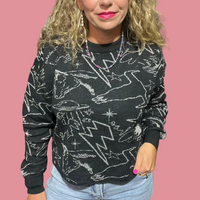 Woman wearing a black sweater with white patterns in an indoor setting