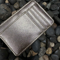 A gold card wallet placed on a bed of rocks.