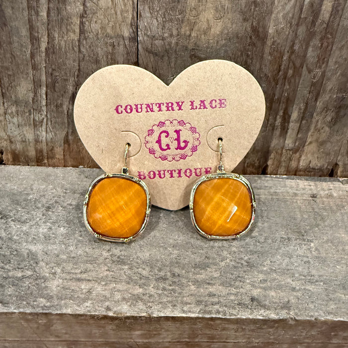 Pair of earrings on a heart-shaped card with 'Country Lace Boutique' branding, placed on a wooden surface.