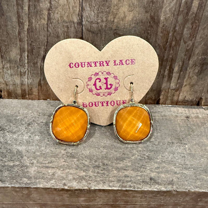 Pair of earrings on a heart-shaped card with 'Country Lace Boutique' branding, placed on a wooden surface.