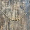 Gold necklace with a clasp on a textured wooden surface