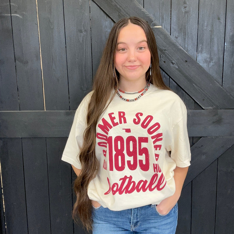 Person wearing a white t-shirt with red text standing against a wooden background