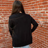 Person wearing a black jacket standing against a brick wall