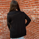 Person wearing a black jacket standing against a brick wall