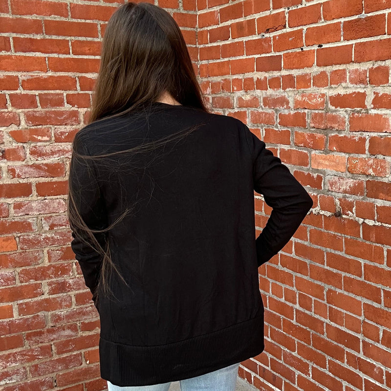 Person wearing a black jacket standing against a brick wall
