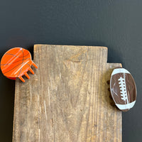 Wooden block with a basketball and football magnet on a dark background