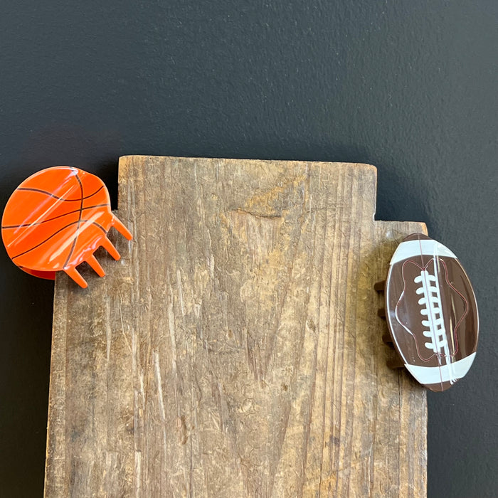Wooden block with a basketball and football magnet on a dark background