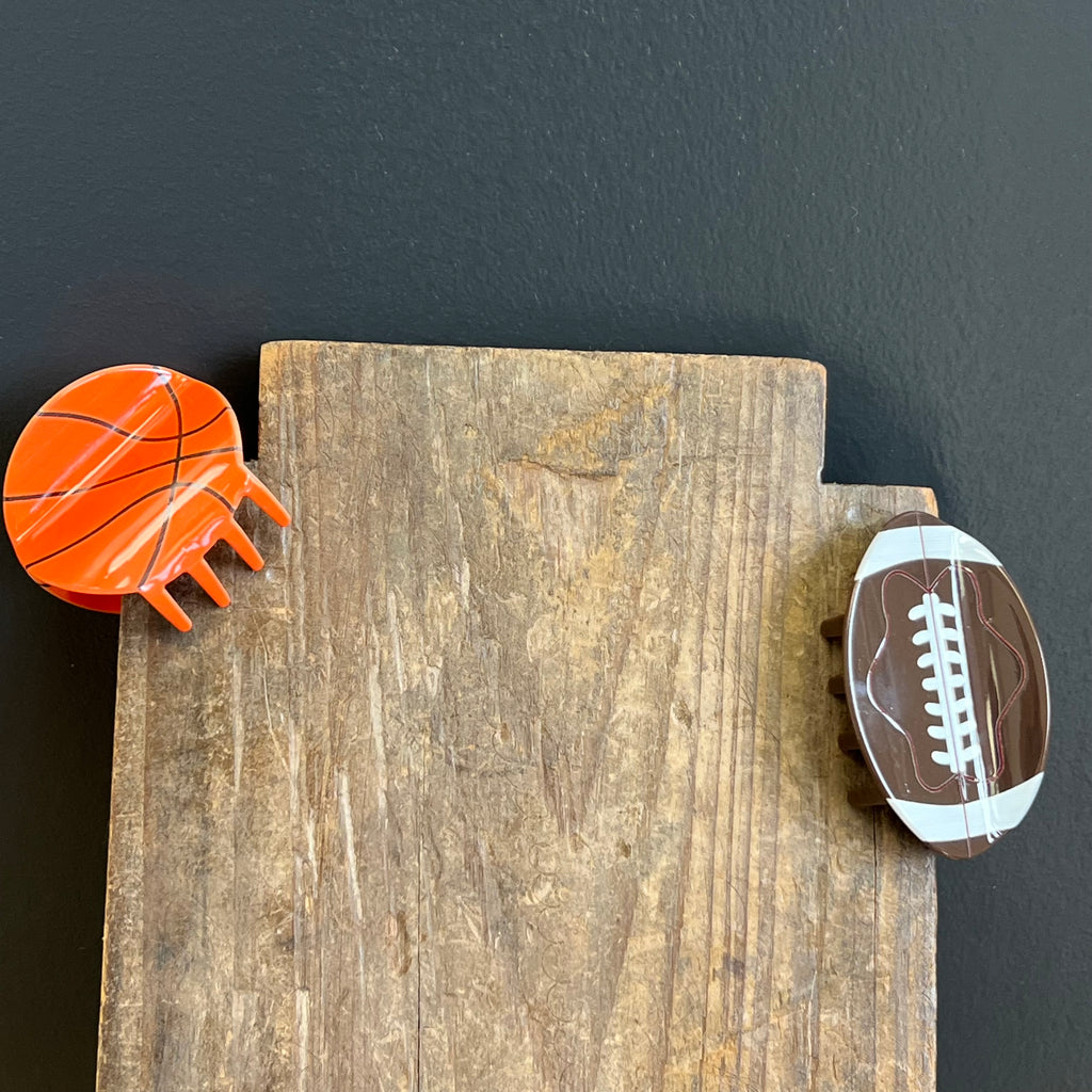 Wooden block with a basketball and football magnet on a dark background