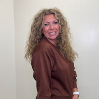 Woman wearing a brown sweatshirt against a plain background