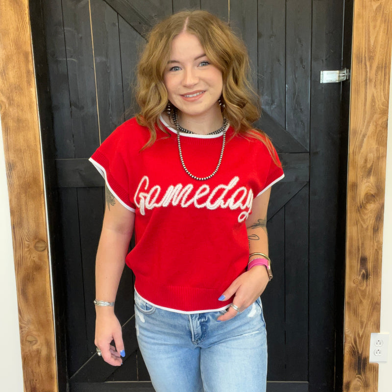 Person wearing a red 'Gameday' sweater standing in front of a black door.