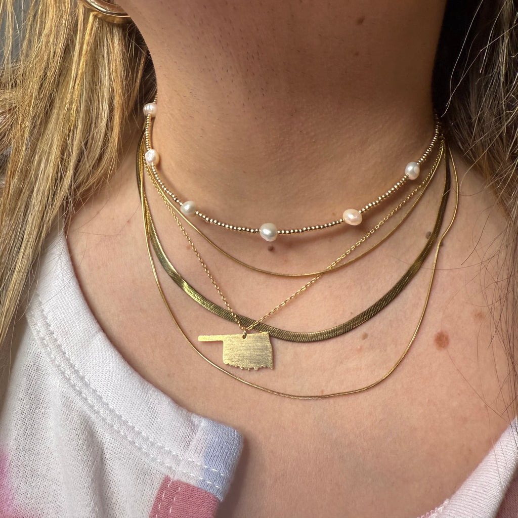 Close-up of a person wearing multiple gold necklaces with a blurred background
