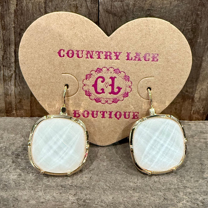 Pair of earrings with a gold frame on a wooden surface