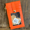 Orange leather cardholder with a product inside on a wooden surface