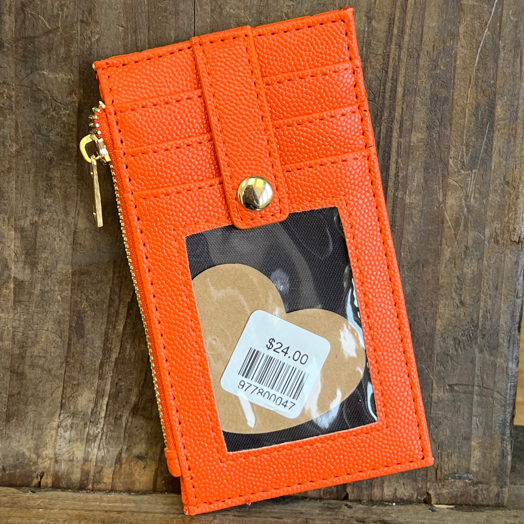Orange leather cardholder with a product inside on a wooden surface