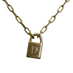 Gold necklace with a lock-shaped pendant on a light gray background