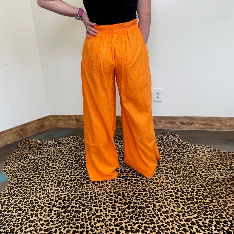 Person wearing bright orange pants standing on a leopard print rug.