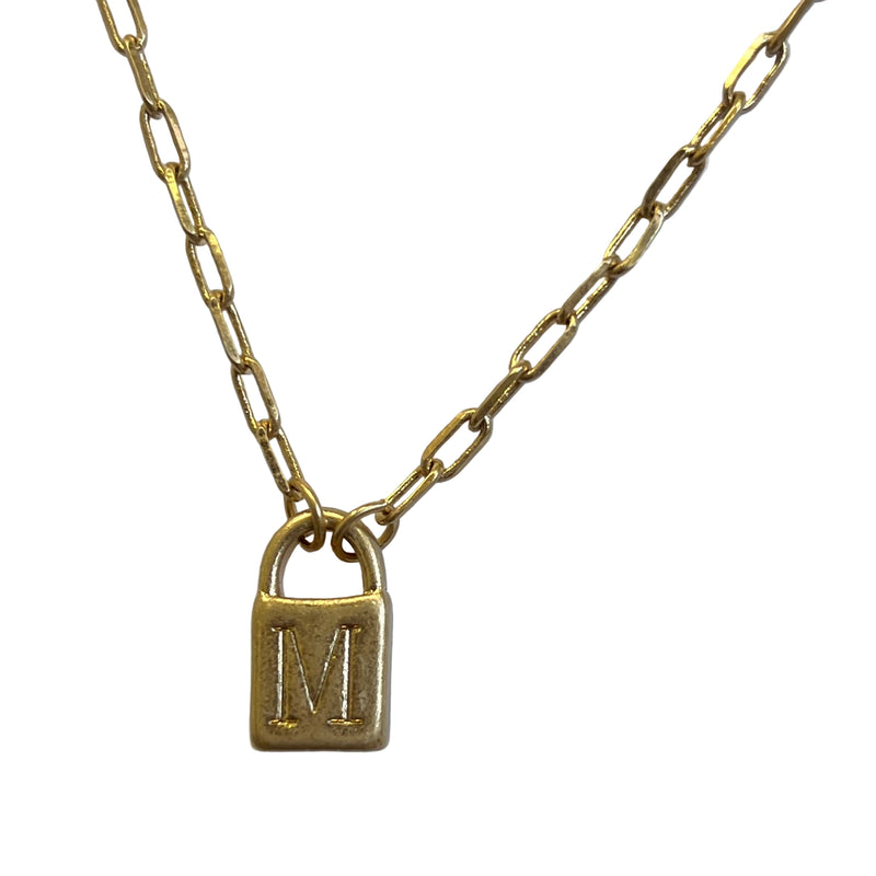 Gold necklace with a lock-shaped pendant featuring the letter 'M' on a light gray background