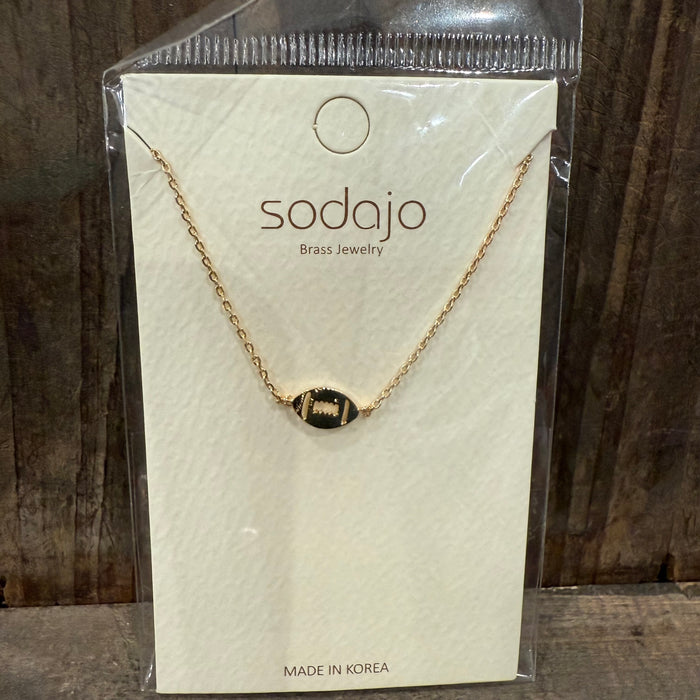Gold necklace on a sodajo branded card with a wooden background