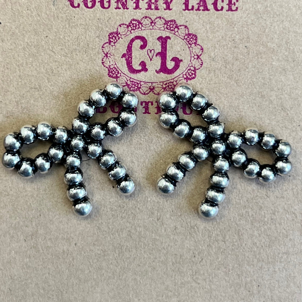 Metallic brooch on a 'Country Lace' branded card against a wooden background
