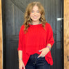 Woman wearing a red sweater standing in front of a wooden door