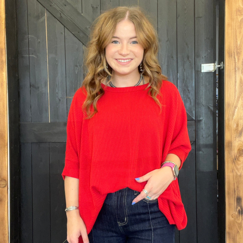 Woman wearing a red sweater standing in front of a wooden door