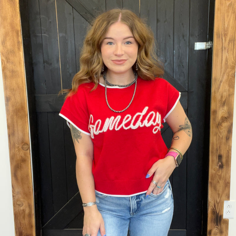 Woman wearing a red 'Gameday' shirt standing in front of a wooden door.