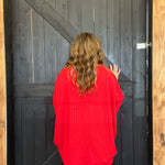 Person wearing a red sweater standing in front of a wooden door.