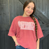 Person wearing a red 'University of Oklahoma' t-shirt against a wooden background