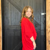 Woman in a red dress standing in front of a wooden door