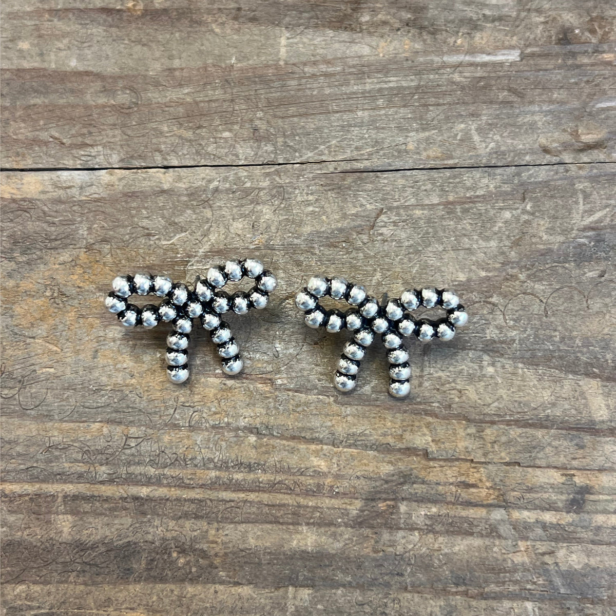 Silver beaded earrings on a wooden surface