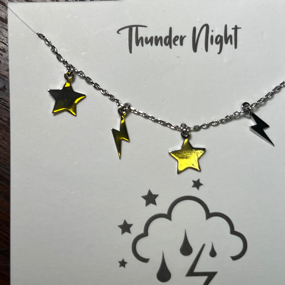 Necklace with star and lightning bolt charms on a 'Thunder Night' card.
