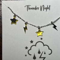 Necklace with star and lightning bolt charms on a 'Thunder Night' card.
