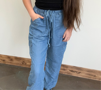 Person wearing blue cargo pants against a plain wall.