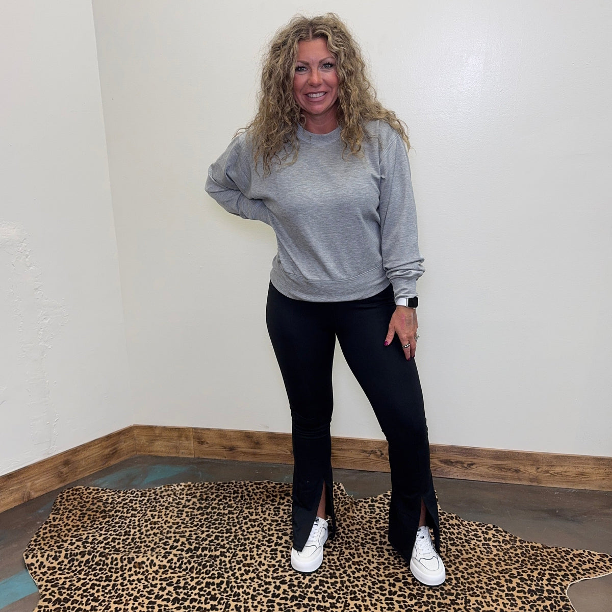 Woman standing on a leopard print rug in a room with white walls and wooden trim.
