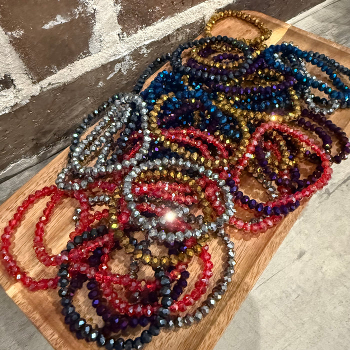 Colorful beaded necklaces on a wooden board with a stone floor background