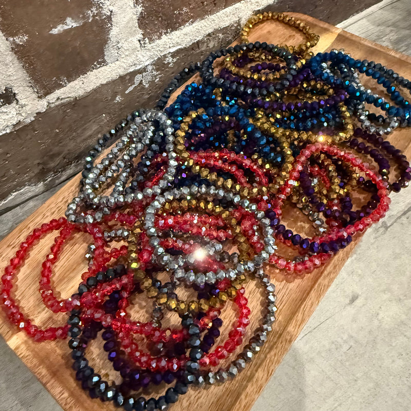 Colorful beaded necklaces on a wooden board with a stone floor background