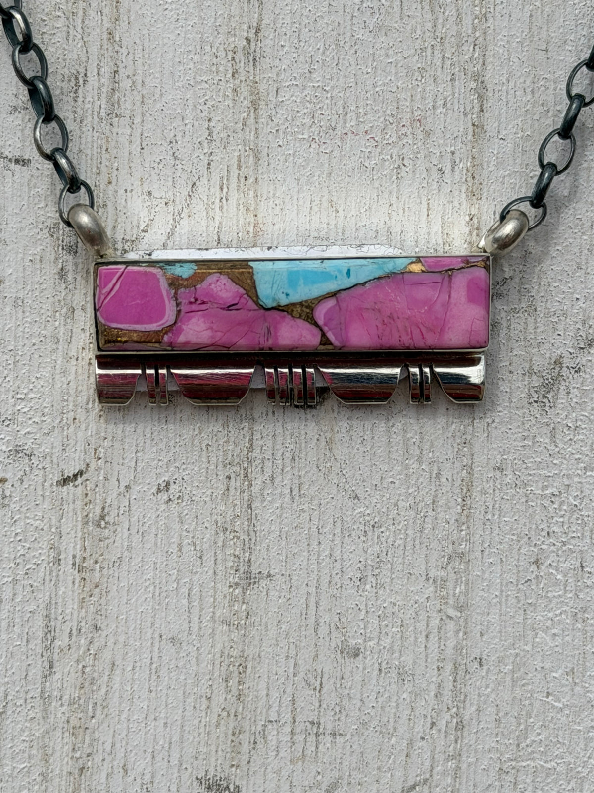 Necklace with a rectangular pendant featuring pink and blue colors on a textured surface