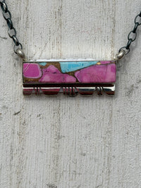 Necklace with a rectangular pendant featuring pink and blue colors on a textured surface