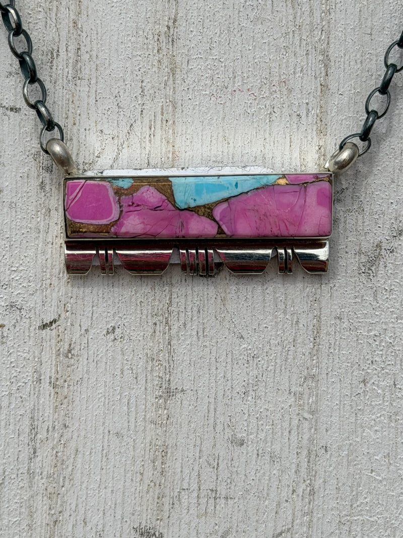 Necklace with a rectangular pendant featuring pink and blue colors on a textured surface