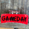 Red sign with 'GAMEDAY' text on a wooden surface