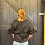 Person wearing a black jacket standing in front of a wooden door