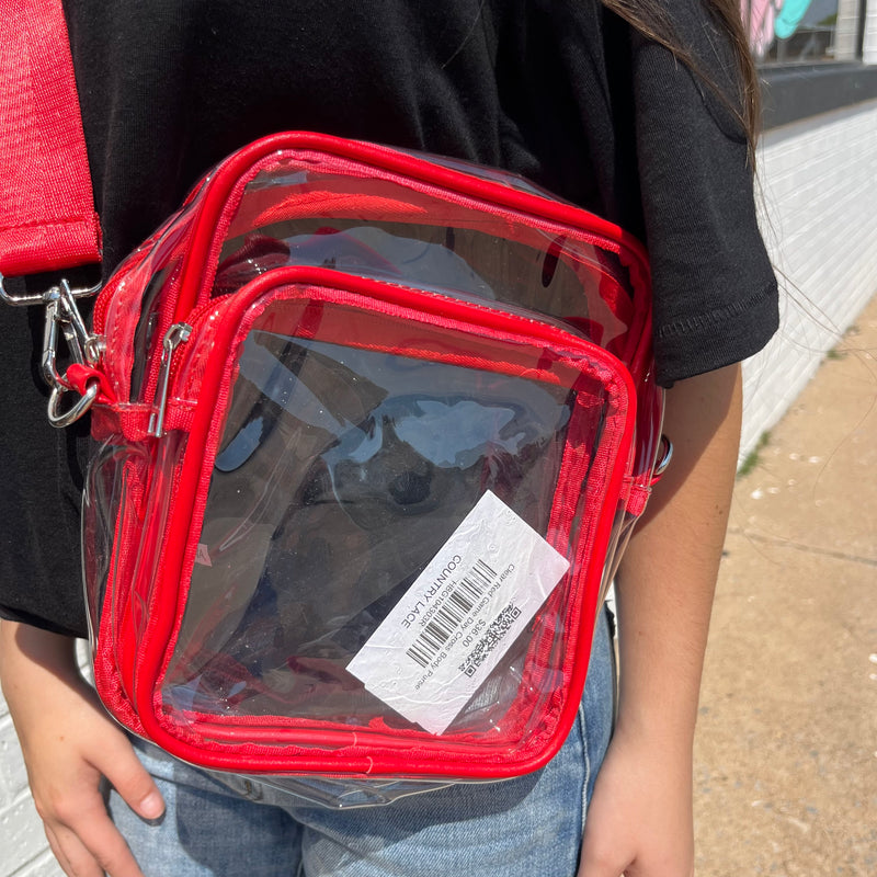 Person holding a transparent bag with red trim outdoors