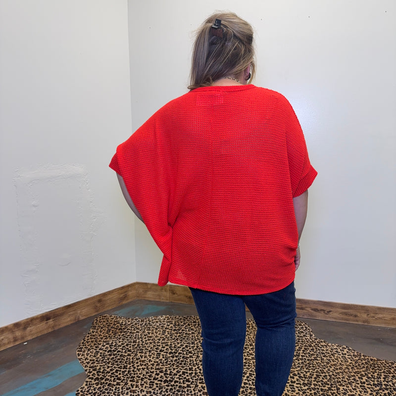 red sweater and blue jeans standing in a room with a leopard print rug.