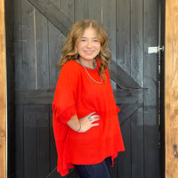 Woman wearing a red sweater standing in front of a wooden door.
