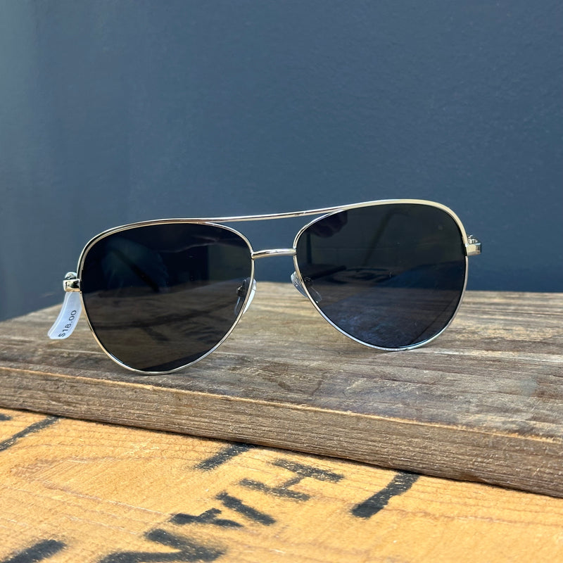 Aviator sunglasses with a tag on a wooden surface against a blue wall