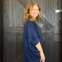Woman in a blue sweater standing in front of a wooden door