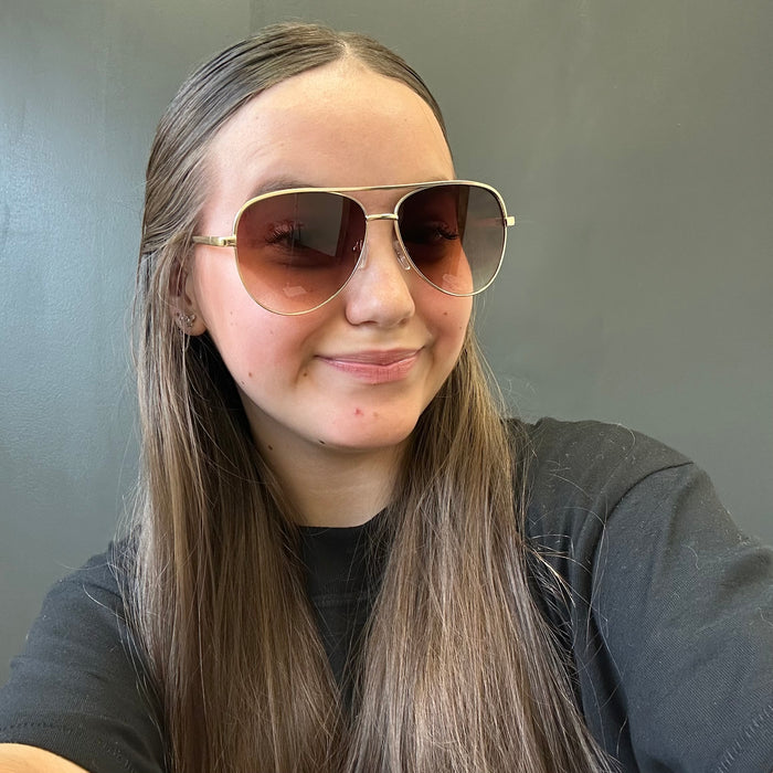 Person wearing aviator sunglasses with a neutral background