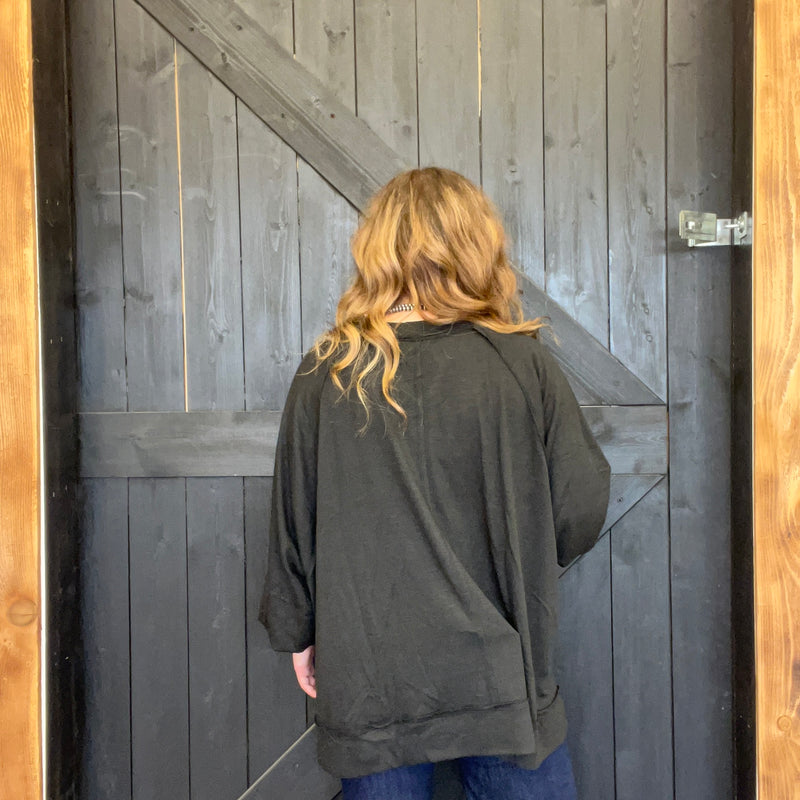 Person wearing a dark jacket standing in front of a wooden door.